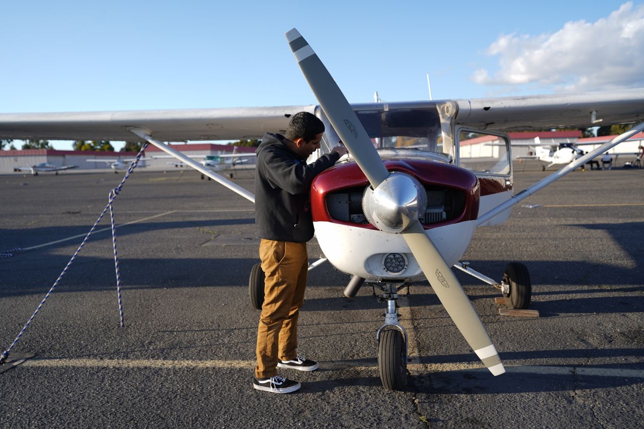 A man inspecting a small airplane at Hayward airfield on a clear day, perfect for aviation enthusiasts.